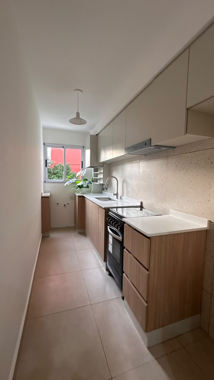 Cocina reformada de Casa M1 con muebles en madera clara y mesada blanca