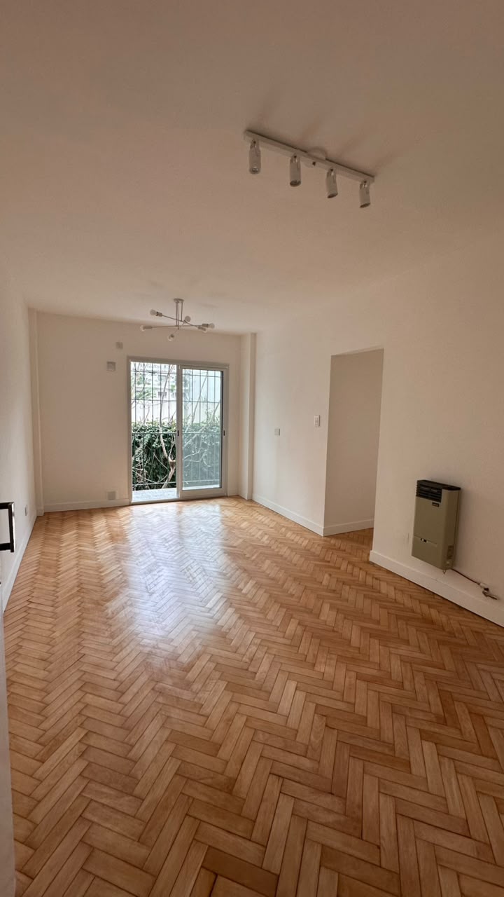 Living comedor de Casa B2 en Flores con piso de parquet espigado restaurado y salida al balcón